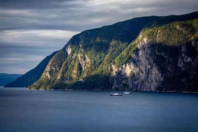 Scenic view of sea by mountains against sky