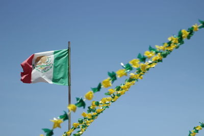 Low angle view of flags against clear blue sky