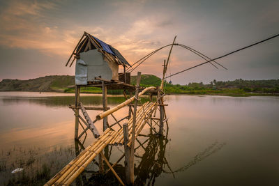 Traditional windmill by lake against sky