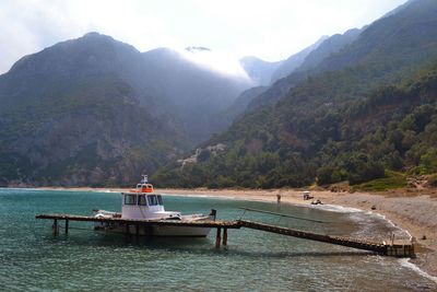 Boat sailing on river by mountains against sky