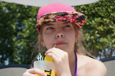 Close-up of thoughtful girl having drink against trees