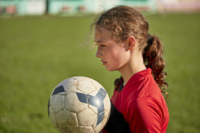 Thoughtful girl with soccer ball on sunny day