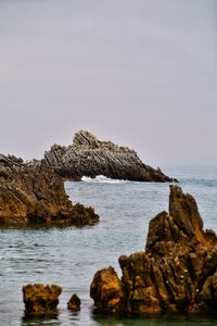 Rocks in sea against clear sky