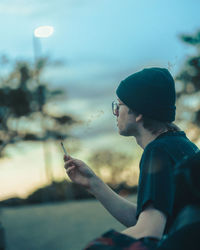 Side view of young man using mobile phone