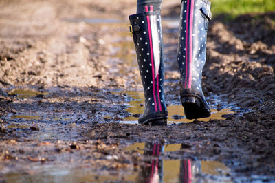 Low section of woman walking on dirt road