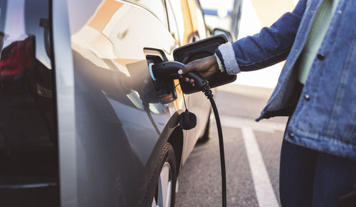 Young woman charging electric car at station