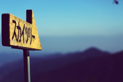 Close-up of road sign against sky