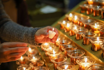 Close-up of hand holding lit candles