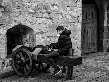 Rear view of man sitting on old building