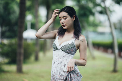 Young woman standing against trees