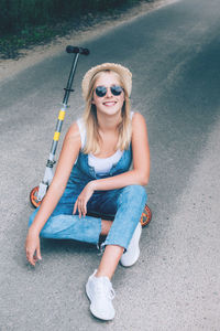 Portrait of smiling teenage girl sitting on road