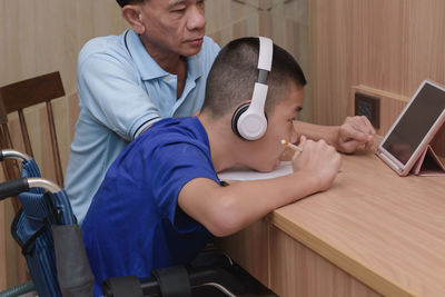 Boy wearing headphones looking at digital tablet at home