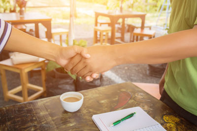 Midsection of woman holding coffee cup on table