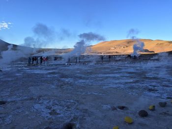 Smoke emitting from volcanic landscape against sky