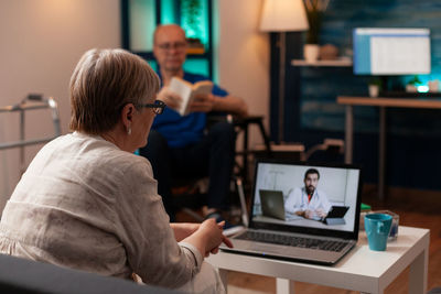 Rear view of woman using laptop at home