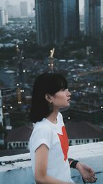 Thoughtful woman standing on building terrace in city