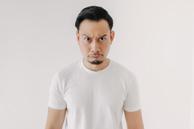 Portrait of young man standing against white background