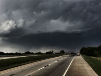 Empty country road against cloudy sky