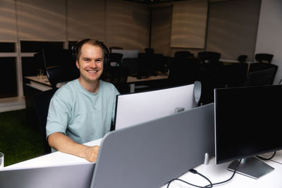 Portrait of businessman using laptop at office