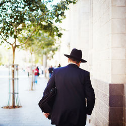 Rear view of man walking on street in city