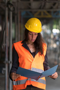 Female construction worker discovering surprising aspects checking plans and office blueprints