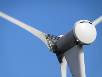 Low angle view of wind turbine against blue sky