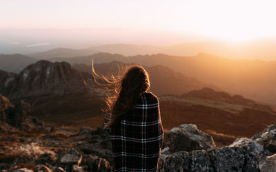 Rear view of person standing on rock against sky