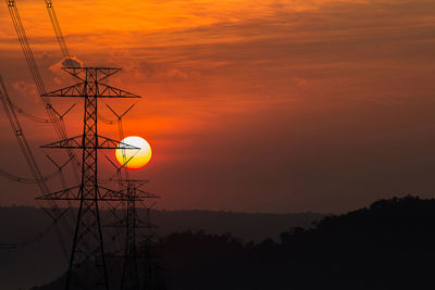 Low angle view of silhouette electricity pylon against sky during sunset