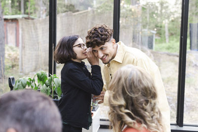 Boy whispering to young man at patio during party