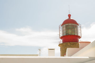 Low angle view of lighthouse by building against sky