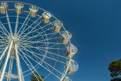 Low angle view of ferris wheel against clear blue sky