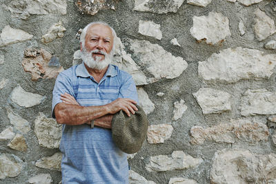 Portrait of a stylish older man wearing a beret on a rock background