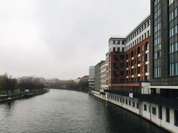 River amidst buildings in city against sky