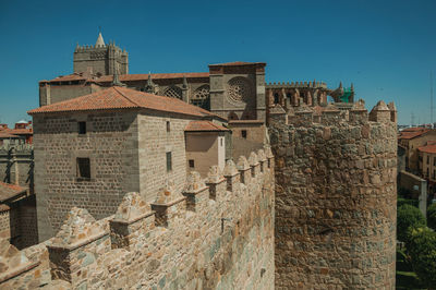 Pathway over stone wall with battlement around the town and side view of cathedral in avila, spain.