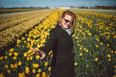 Woman standing on yellow narcissus flower field