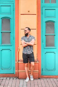 Full length of young man standing against door of building