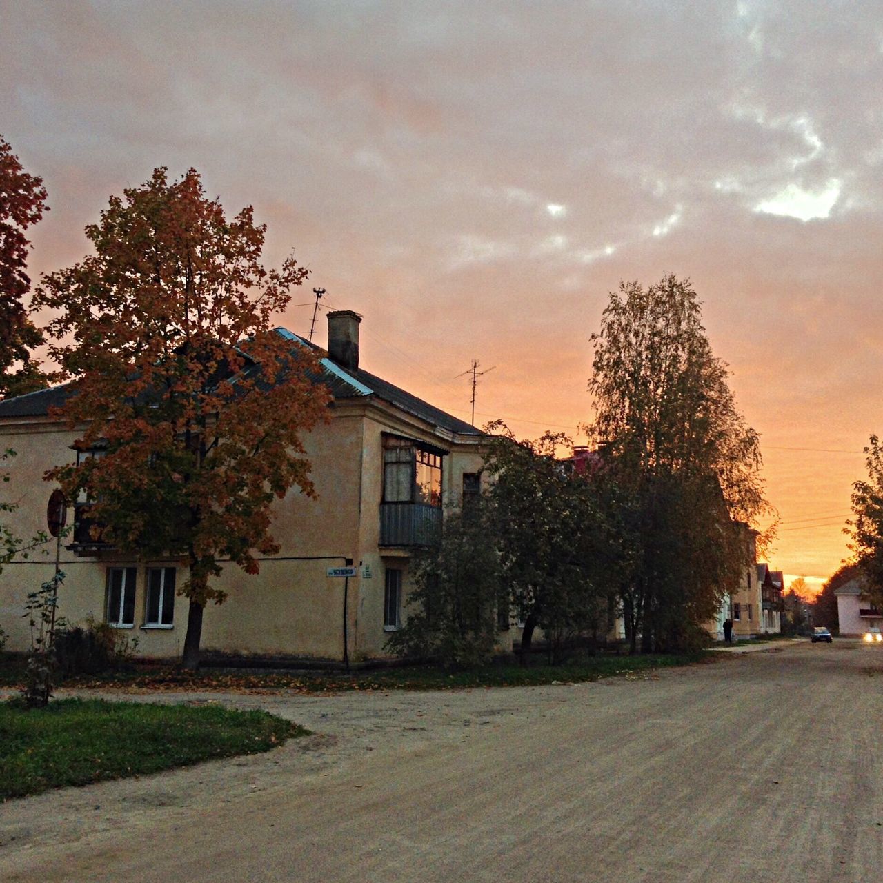 building exterior, architecture, built structure, tree, sky, sunset, house, cloud - sky, car, land vehicle, street, residential structure, residential building, city, transportation, road, cloudy, building, mode of transport, outdoors