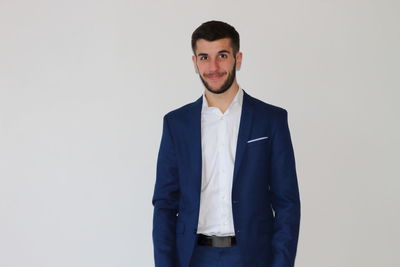 Portrait of young businessman standing against white background