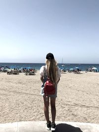 Woman standing on beach against clear sky