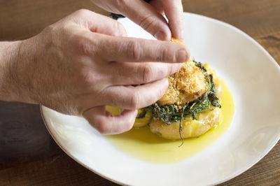 Close-up of person holding bread in plate on table