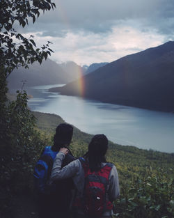 Rear view of people looking at mountains against sky