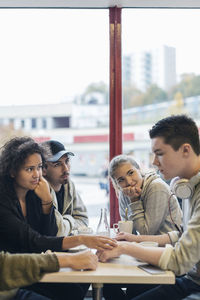 University students looking at sad friend in cafe