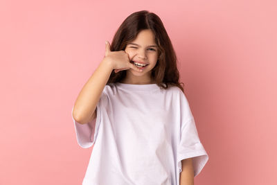 Portrait of young woman against pink background