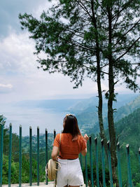 Rear view of woman standing by plants against sky and the biggest lake