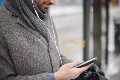 Elegant man with smartphone waiting on bus stop