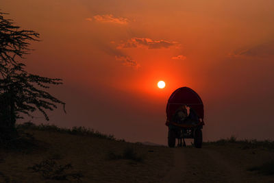 Ox cart at desert against orange sky