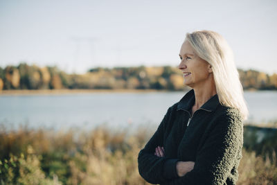 Thoughtful female farmer standing arms crossed at organic farm