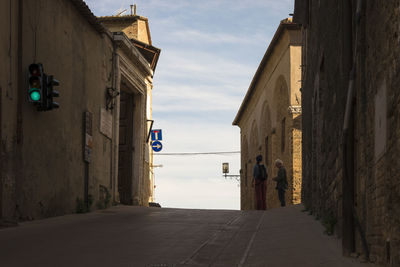 Rear view of people on footpath amidst buildings