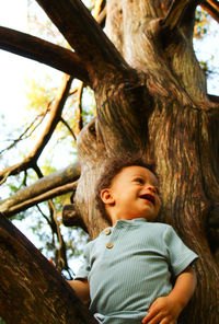 Portrait of toddler looking away against tree trunk