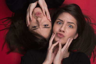 Portrait of young women lying over red background